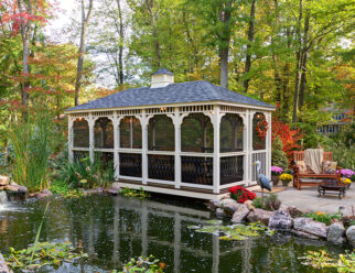 10'x20' Rectangular Baroque Style Tan Vinyl Gazebo With Screens Next To A Backyard Pond