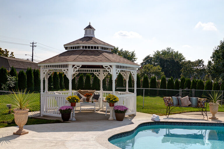 14' Octagonal Colonial Style White Vinyl Gazebo With Pagoda Style Roof And Black Shingles Next To Backyard Pool