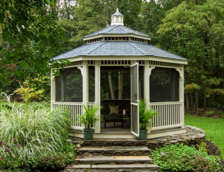 16′ Octagon, Country Style Tan Vinyl Gazebo With Black Shingled Pagoda Roof In A Backyard Garden