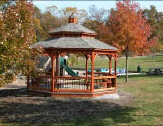 16′ Octagon Gazebo Shown with Cedar stain, Benches, Baroque railing, Pagoda roof, Cupola and 30 year architectural shingles.