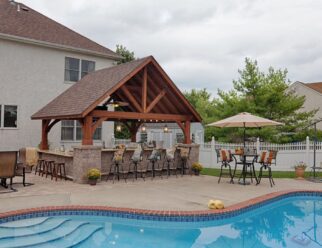 16’ x 14’ Alpine Cedar Wood Pavilion With Canyon Brown Stain and Asphalt Shingles In A Backyard Pool Patio Setting