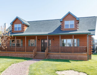 ront view of 28×52 Mountaineer Deluxe Cabin with Prow Roof, (2) 8' A-Frame Dormers, Log Corners, and 6-lite Signet Fir Entry Door with Stained Sidelites