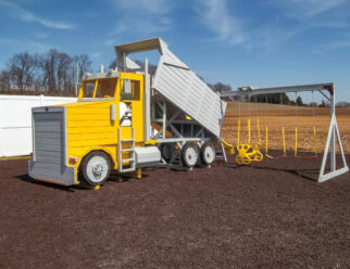 Model 1700 Dump Truck 18'x6'x12' Playset with 144 sq. ft. of Play Deck, Ground Level Deck, 4', 5', and 7' High Decks, Air Horns, Mirrors, Smoke Stacks, Gas Tanks, 4 Entry Ladders, Headlights, Air INtakes, 2 Belt Swings, 1 Double Glider, 3-Position Swing Beam, 10' Wave Slide, 14' Sidewinder Slide, and 2 Steering Wheels