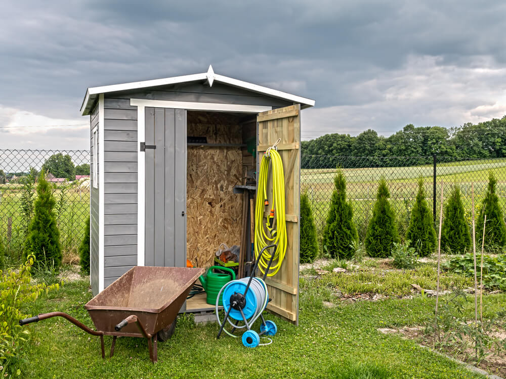 Shed is open and lawn care items are pulled out to take inventory.