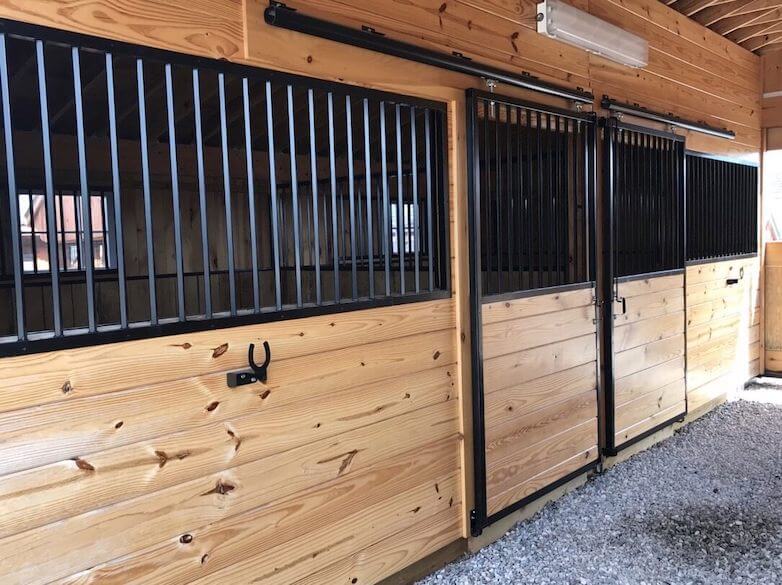 Inside a custom horse barn with new wood and freshly painted iron bars.