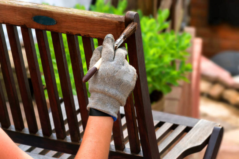 A woman paints a wooden chair to freshen it up.