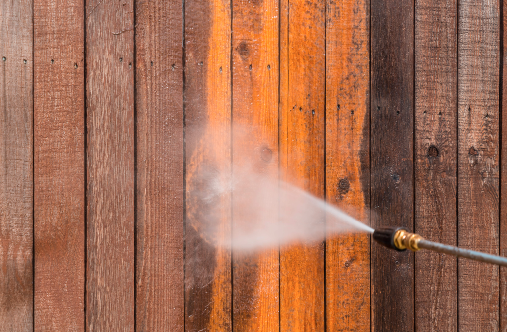 A photograph of a pressure washer spraying wooden siding.