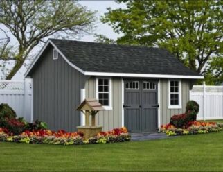 Gray Cape Elite Shed With Grey Doors And A Black Shingle Roof With A Wishing Well Near The Entrance