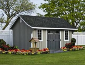 Gray Cape Elite Shed With Grey Doors And A Black Shingle Roof With A Wishing Well Near The Entrance