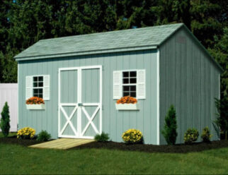 Green Wooden Carriage Shed With White Accents Around Doors and White Shutters With Flower Boxes