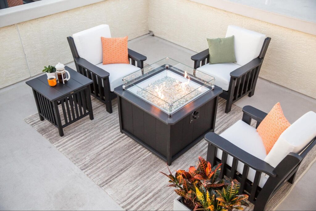 A smaller patio with three chairs and a fireplace in between them. 