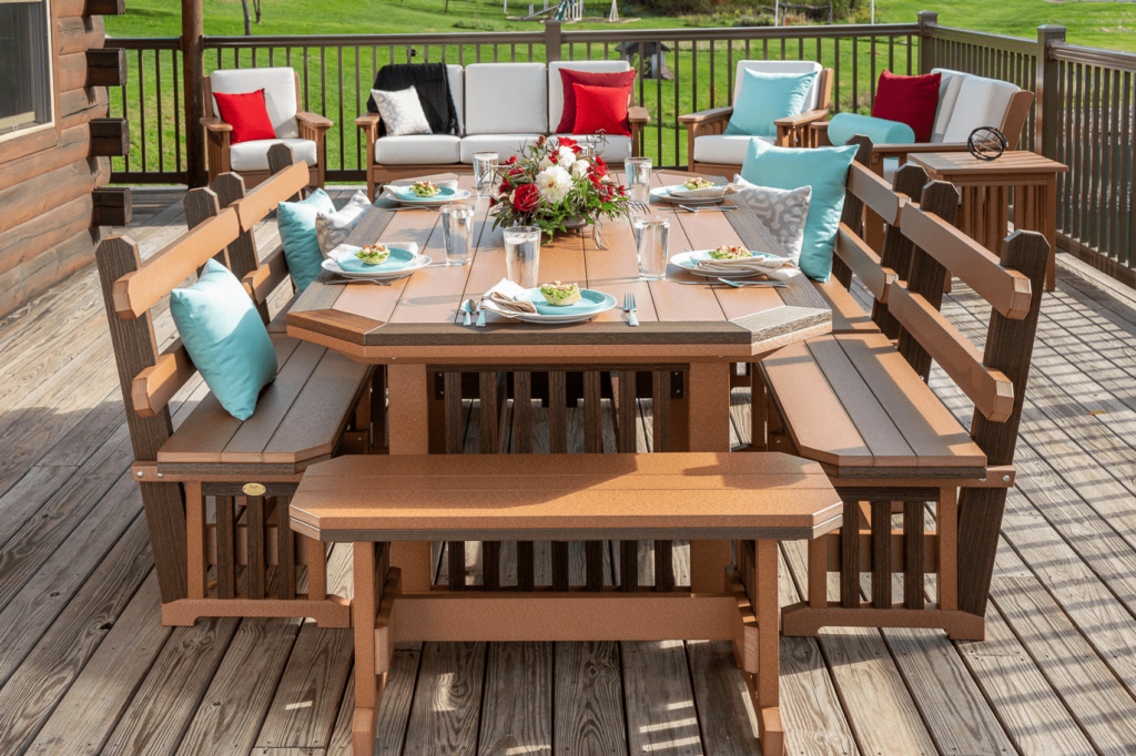 A close-up of a patio table set with a floral centerpiece and pillows on the benches. 