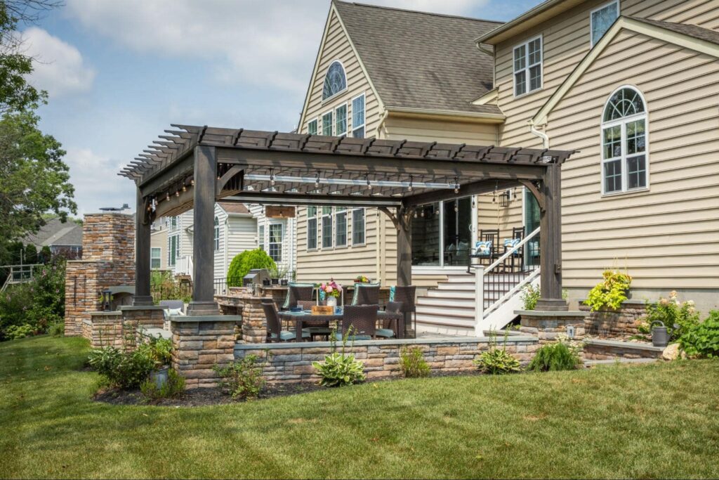 a wooden pergola with an outdoor kitchen underneath.