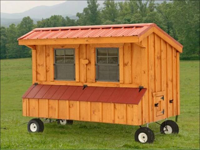 a wooden chicken coop on wheels in a grassy field