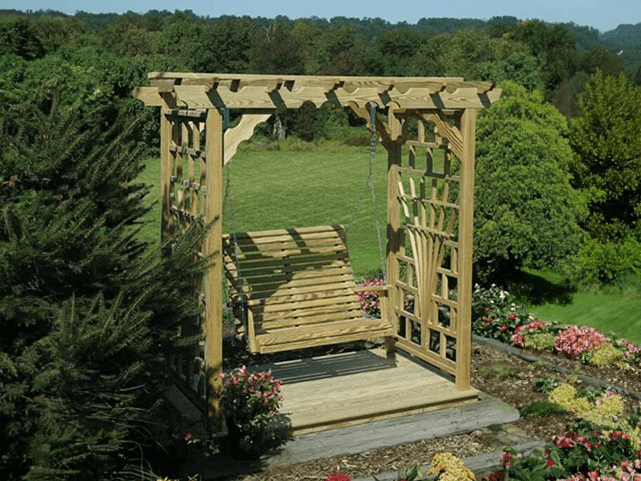 Wooden arbor with a swing overlooking a field for privacy landscaping
