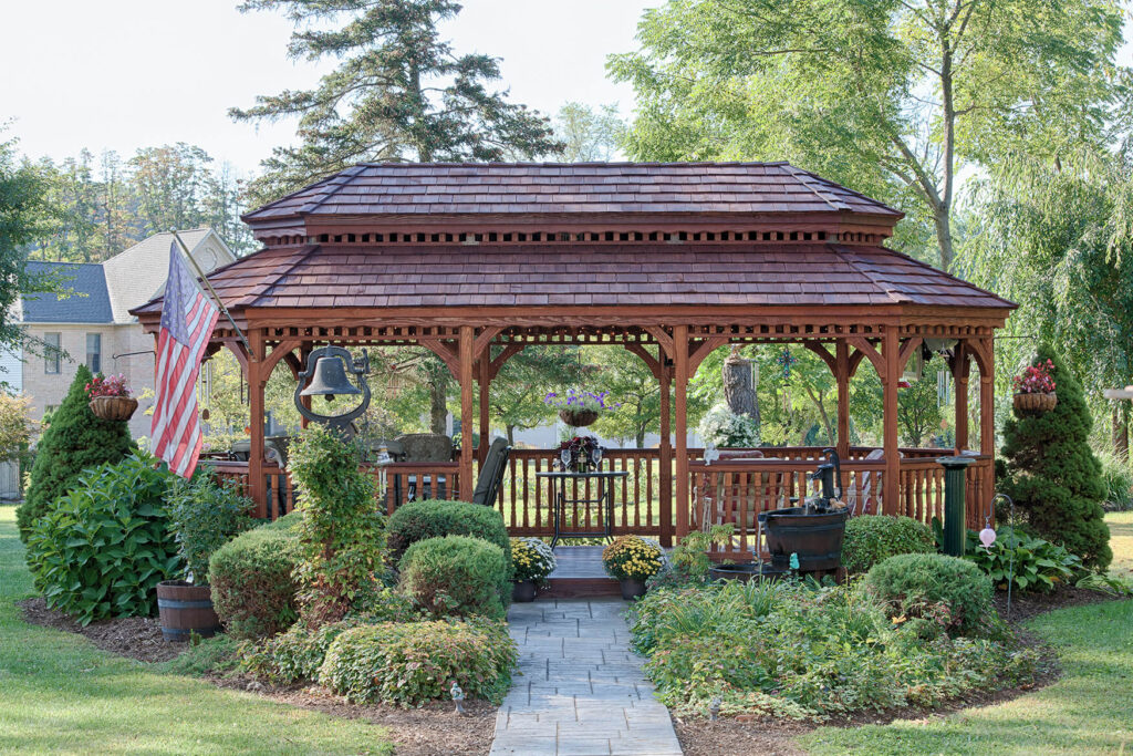 Oval wood gazebo with a tiered roof and a sidewalk leading to it