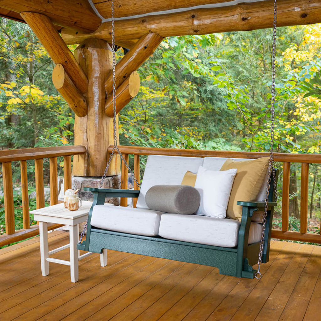 A blue porch swing with white cushions and a side table