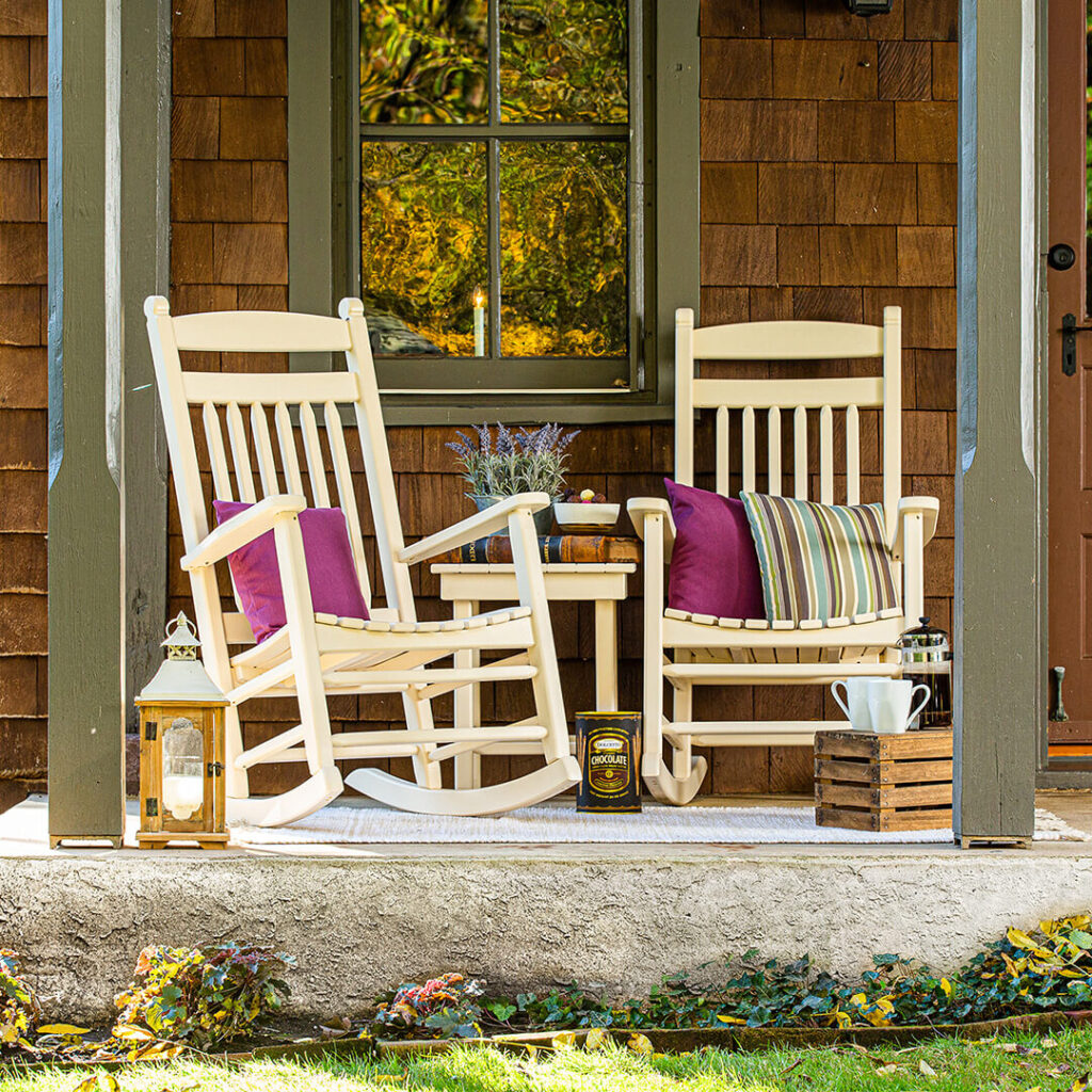 Two white rocking chairs on a porch