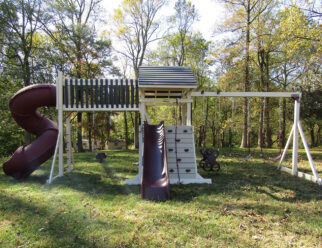 White and red vinyl swing set with a spiral slide, rock wall, and several swings