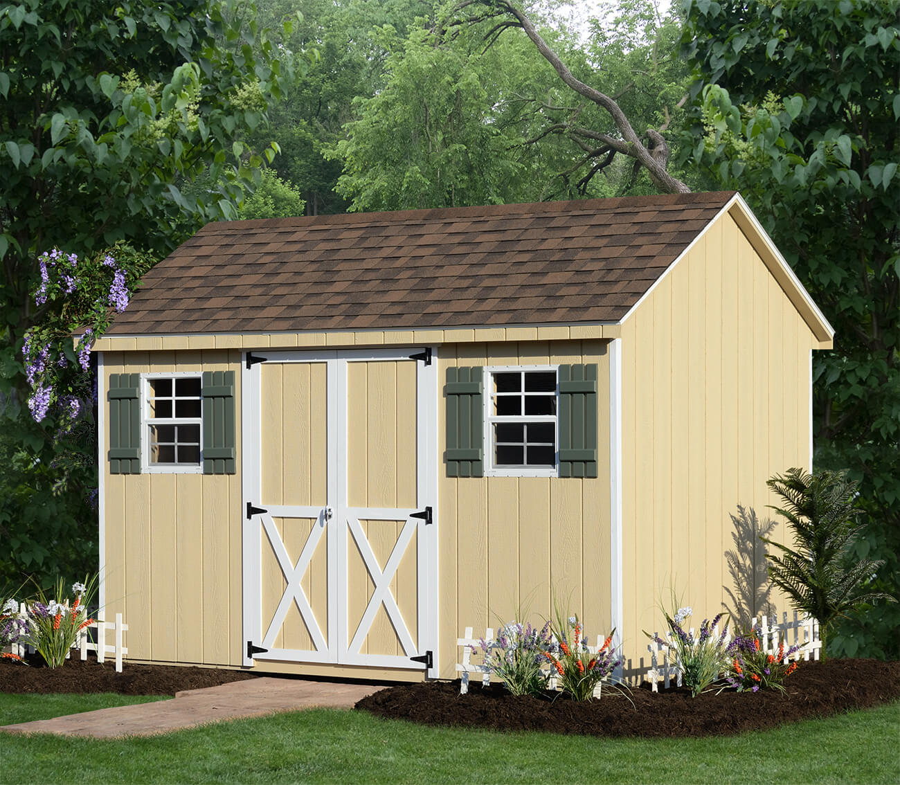 Yellow wooden shed with green shutters and flowers around it