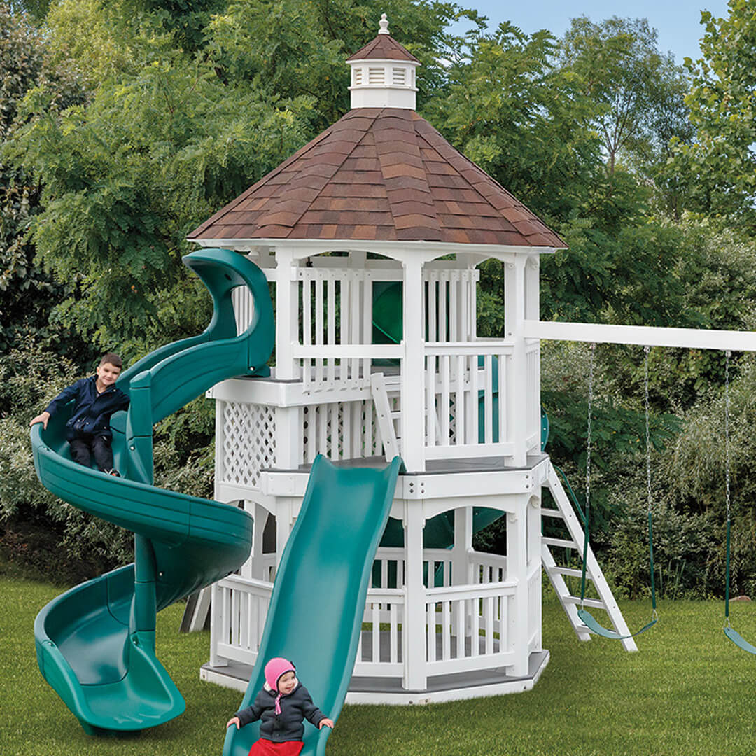 White gazebo towers on a swing set with a green spiral slide and brown shingled roof